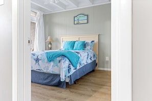 Ein Schlafzimmer mit einem Bett, einem Nachttisch, einer Lampe, einem Wandzeichen und einem Holzboden.