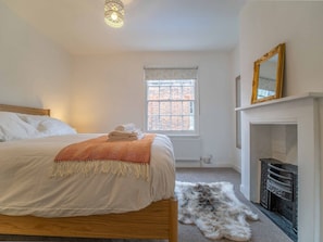 A bedroom with a bed, a fireplace, a window, and a mirror. - City Centre Cottage | Canterbury  | Garden & Views (Kent)