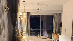 Un salon moderne avec un canapé, une table basse et un lit offrant une vue sur la ville la nuit.