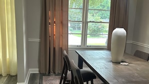 A dining area with a wooden table, chairs, a vase, and a view through large windows. - Peaceful Atlanta Stay.
Walk to Lake & Trail. Cozy & Quiet (Tucker)