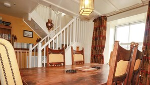 A dining area with a wooden table, chairs, a staircase, and a hanging light fixture. - Trelake Cottage (Tintagel)