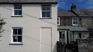 A two-story building with white walls, multiple windows, and a stone entrance. - Trelake Cottage (Tintagel)