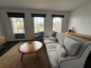 A living room with a sofa, a wooden coffee table, a chair, and a window with blinds. - 400m from the beach! (Semaphore)