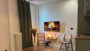 Un salon moderne avec une cheminée, une table à manger, deux chaises et un coin cuisine.