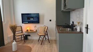 Une cuisine moderne équipée d’un four à micro-ondes encastré, d’un évier et d’un coin repas en bois avec deux chaises.
