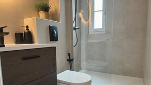Une salle de bain moderne comprenant des toilettes, un espace douche et un meuble-lavabo avec des tiroirs.