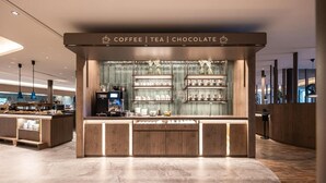 A modern coffee shop with a wooden counter and shelves of coffee, tea, and chocolate. - Das Gerstl Family Retreat (Curon Venosta)