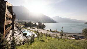 A hotel with a pool, outdoor seating, and a view of a lake and mountains. - Das Gerstl Family Retreat (Curon Venosta)