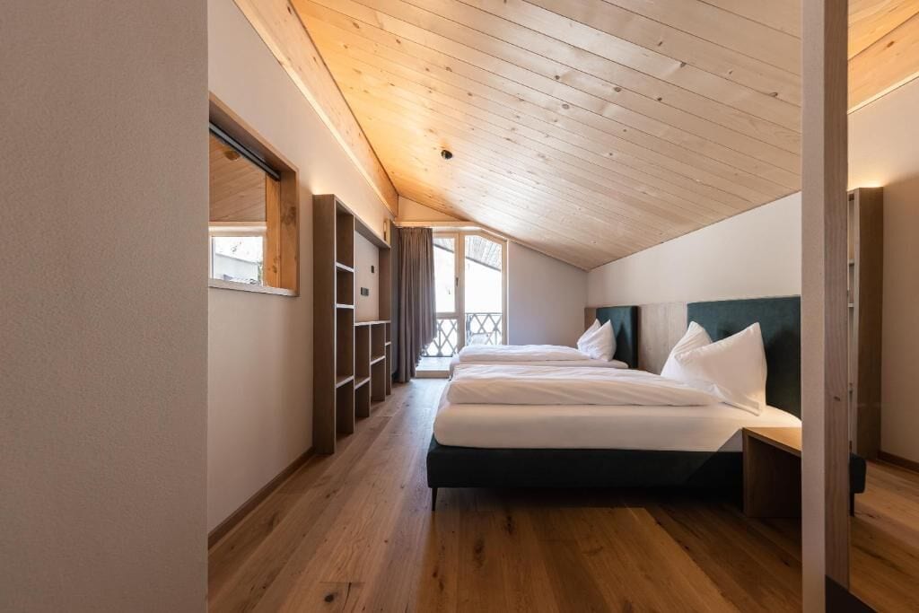 A bedroom with a wooden ceiling, a bed, a nightstand, and built-in shelving.