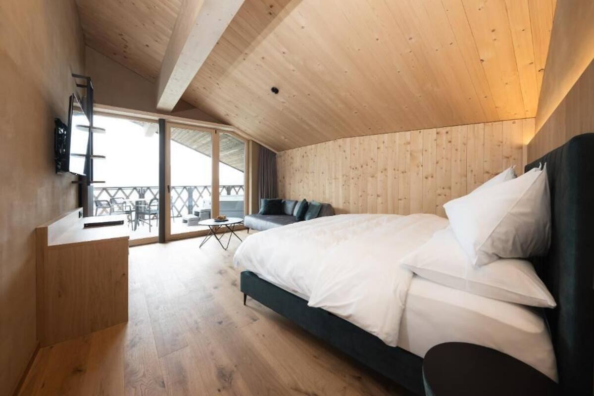 Un dormitorio con cama, escritorio, televisión y balcón.
