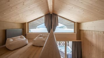 Une pièce aux hauts plafonds, avec des poutres en bois, une grande fenêtre et un jacuzzi visible à travers cette fenêtre.