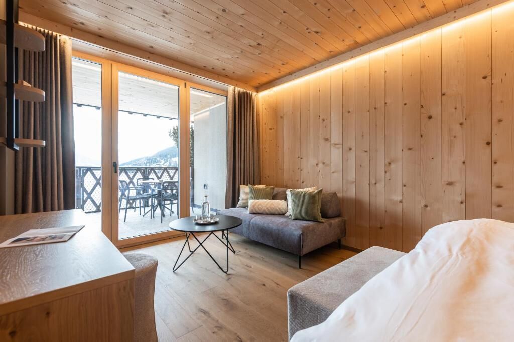 A wooden-paneled room with a sofa, a small round table, and a bed.