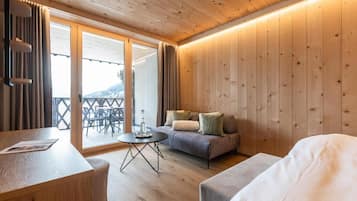 A wooden-paneled room with a sofa, a small round table, and a bed.