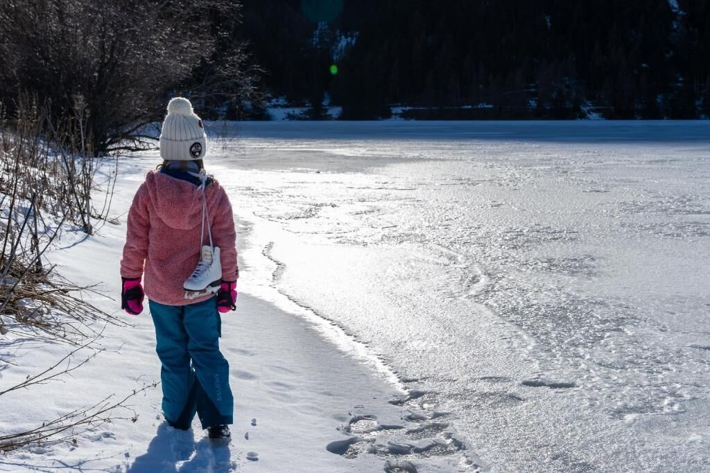 A person walking on a frozen body of water with trees in the background.