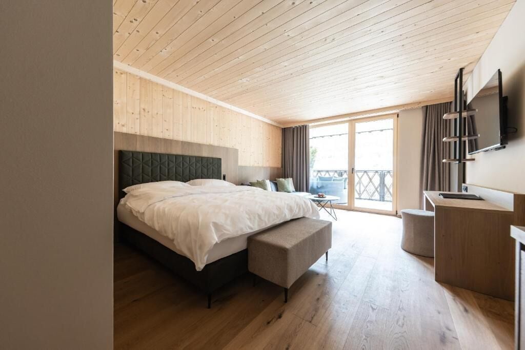 Een slaapkamer met een bed, een bureau, een stoel en een balkon.