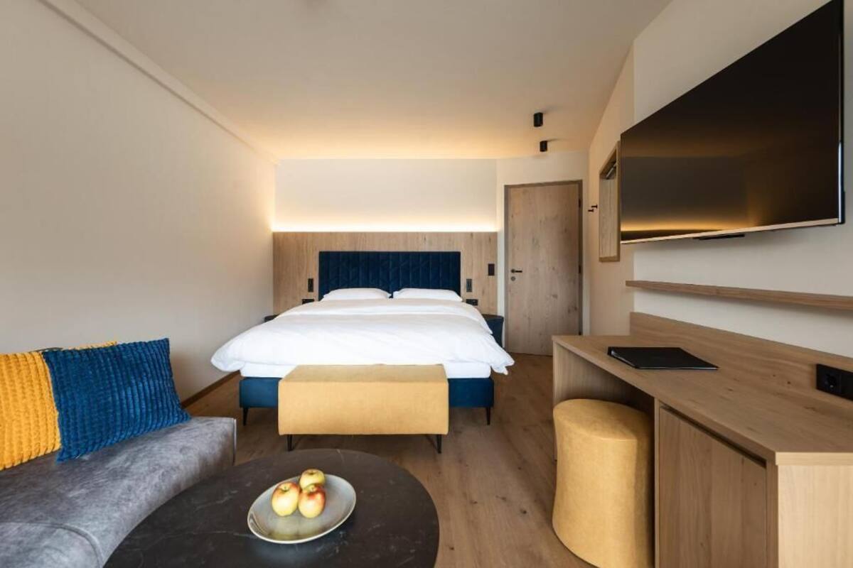 Una habitación de hotel con una cama, un escritorio, un televisor y un sofá.