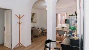 Una habitación con un perchero de madera, un escritorio con lámpara y una silla.