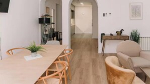 Un comedor con una mesa y sillas de madera, un sofá y una planta pequeña.