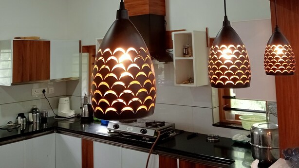 Una cocina con armarios de madera, estufa y lámparas colgantes con diseño ondulado.