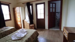 A room with two beds, a wooden wardrobe, a small stool, and a door leading to another room.