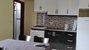 A compact kitchen with a washing machine, a stove, and a refrigerator.