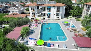 A hotel with a swimming pool, multiple balconies, and a view of the surrounding town.