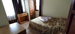 Une chambre à coucher avec un lit, une table de chevet en bois, une armoire et une fenêtre avec des rideaux.
