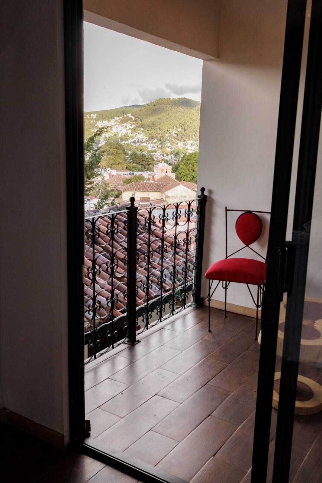 Un balcó amb una cadira vermella, vista d'una vila i un paviment de rajoles.