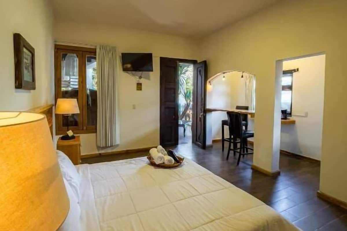 A hotel room with a bed, a desk, a chair, and a television.