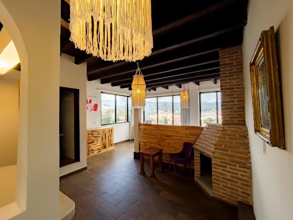 A spacious room with a fireplace, wooden seating, and large windows.