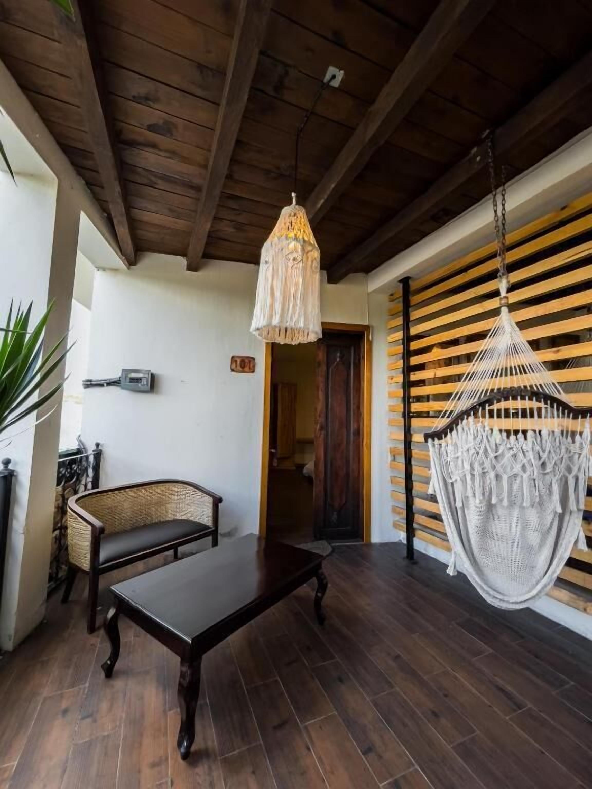 A wooden ceiling, a hanging chair, a bench, and a doorway.
