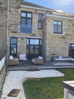 A stone building with a balcony, outdoor seating, and a gravel pathway.