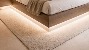 Un dormitorio moderno con cama, mesita de noche y alfombra.