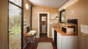 Een kleine keuken met houten wanden, een eethoek met een tafel en stoelen, en uitzicht op de omgeving.