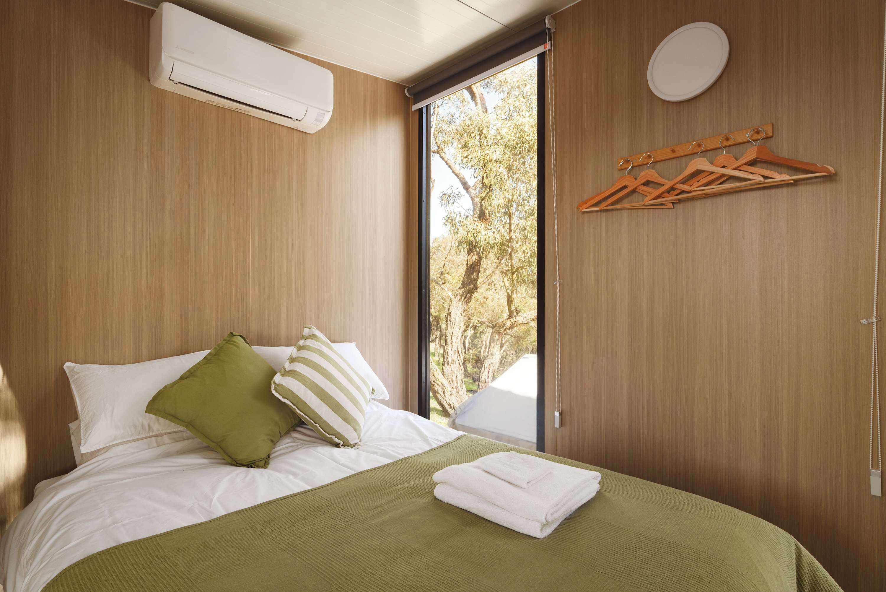 Une chambre d’hôtel avec un lit, une fenêtre et un climatiseur fixé au mur.