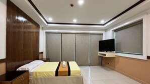 Una camera d'albergo con un letto, una TV, un armadio e una finestra.