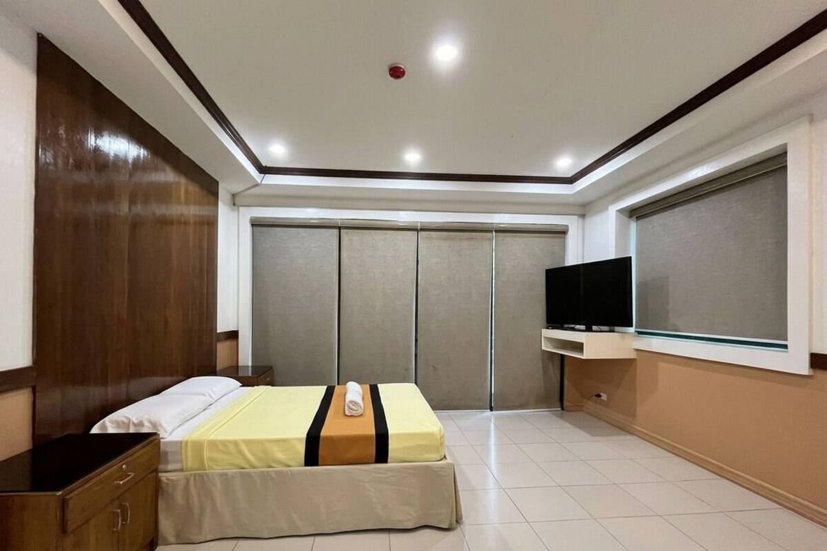Ein Hotelzimmer mit Bett, Fernseher, Kleiderschrank und Fenster.