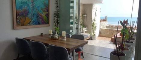 A dining area with a wooden table, chairs, and a painting on the wall.