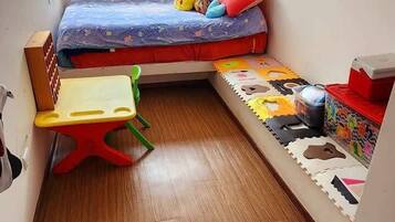 A small, compact room with a bunk bed, a small table, and a storage unit.