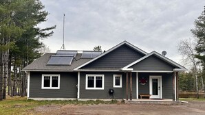 Et toetagers hus med skrå tag, solpaneler og en veranda.