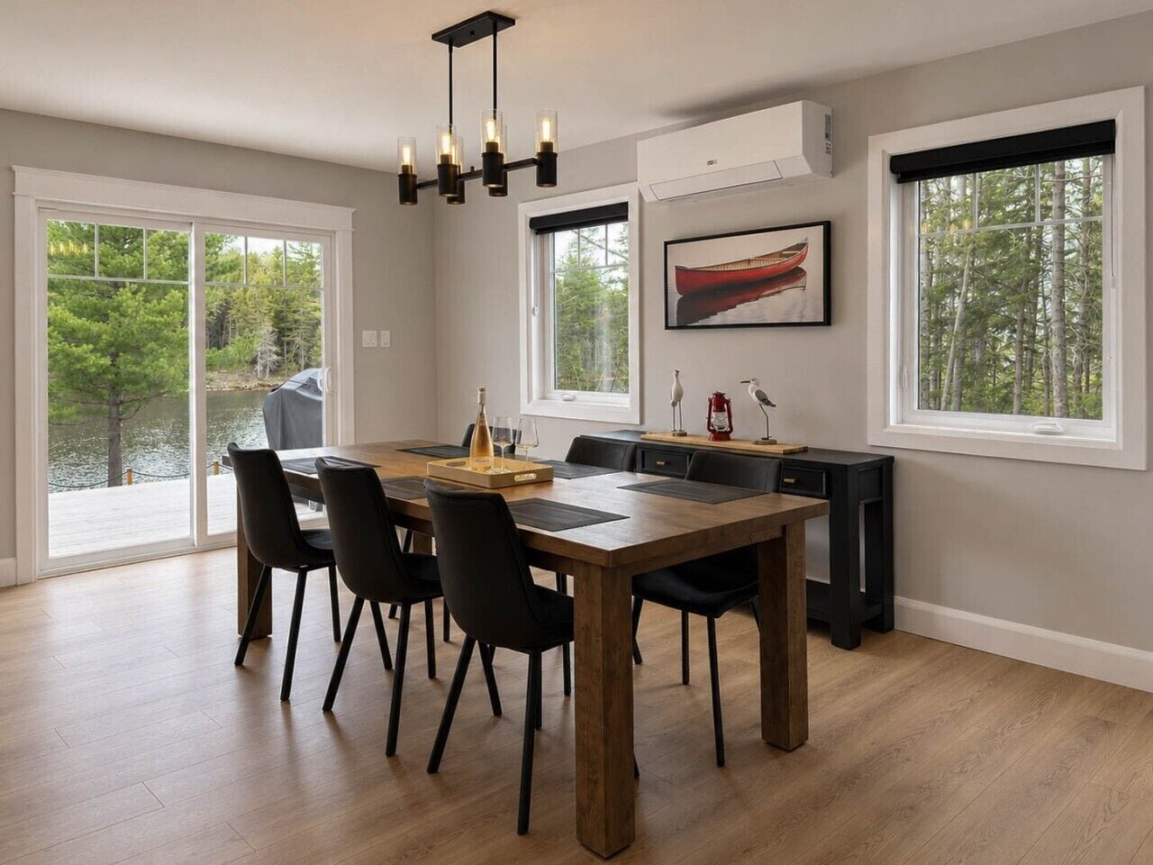 Un coin repas avec une table en bois, des chaises noires et un lustre.