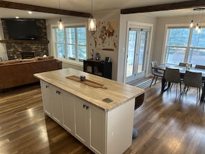 Una cocina moderna con una isla central, suelo de madera y un comedor con sillas.
