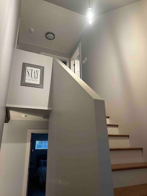 A staircase with a sign that reads 'STAY a while' and a light fixture above it. - Waterfront | Kayaks | Screened Patio | Bonfire (Upper Rexton)