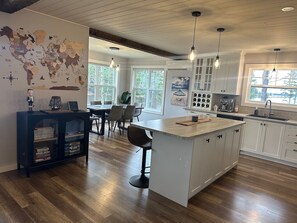 Una cocina moderna con una isla central, suelo de madera e iluminación colgante.