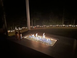 Feuerecke mit Flaschen und Blick auf die nächtliche Landschaft.