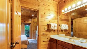 A wooden cabin bathroom with a large mirror, wooden cabinets, and a bench in the corner. - Private 8BR Gatlinburg Cabin w Amazing Views (Gatlinburg)