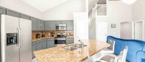 A modern kitchen with granite countertops, stainless steel appliances, and a built-in island with seating.