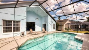 A swimming pool with a covered area, lounge chairs, and a ceiling fan. - Disney Area 5BR With Pool Spacious and Prime Location (Kissimmee)