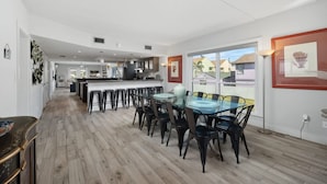 A spacious kitchen with modern appliances, a dining area with a glass table, and a view of the neighborhood. - Ocean Breeze Escape South Padre Island (South Padre Island)