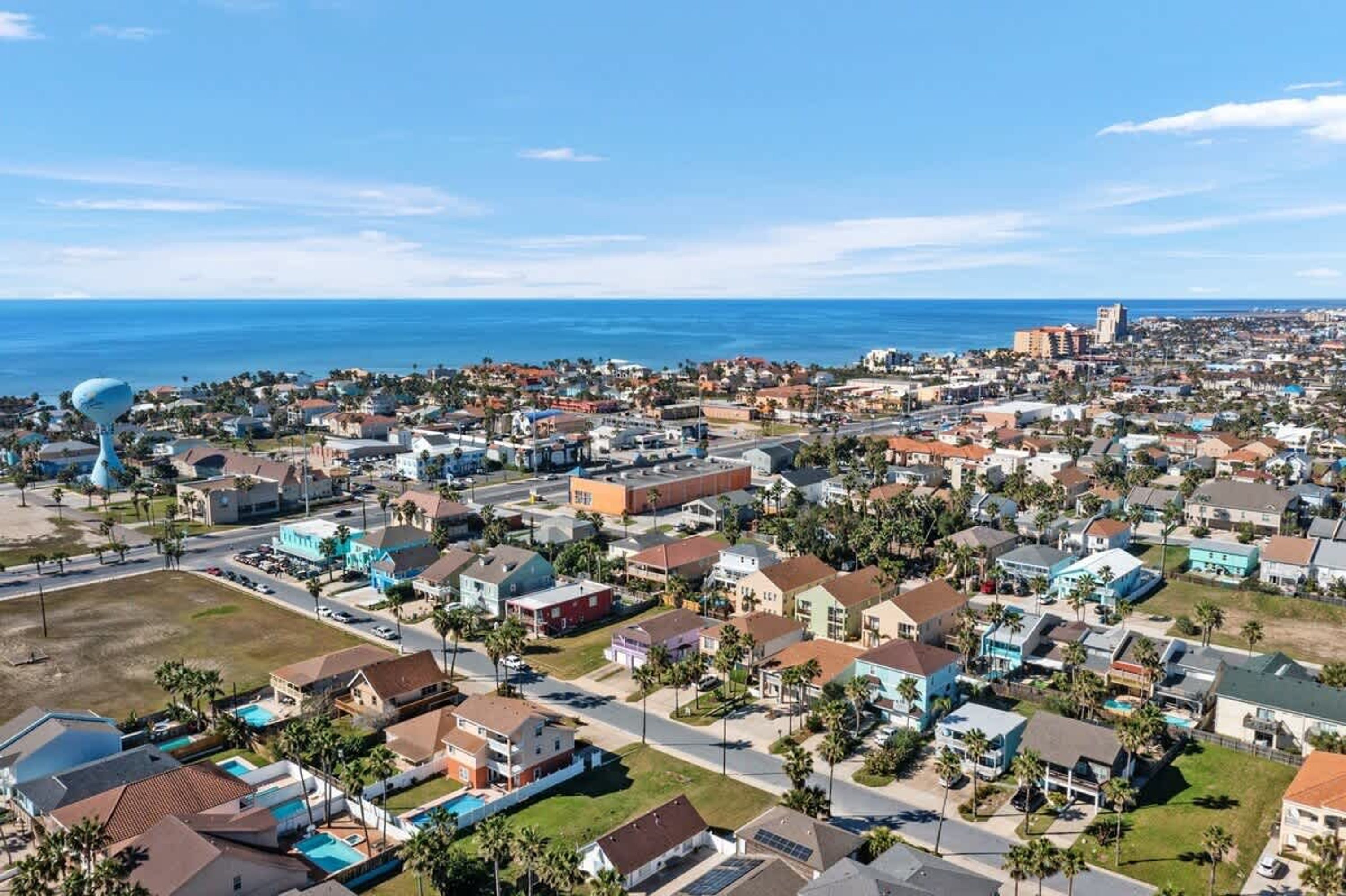 A coastal residential area with houses, a large blue sculpture, and a clear view of the ocean.
